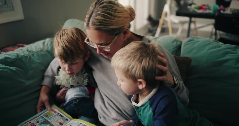 Mother and two boys sitting on the couch looking at a comic book