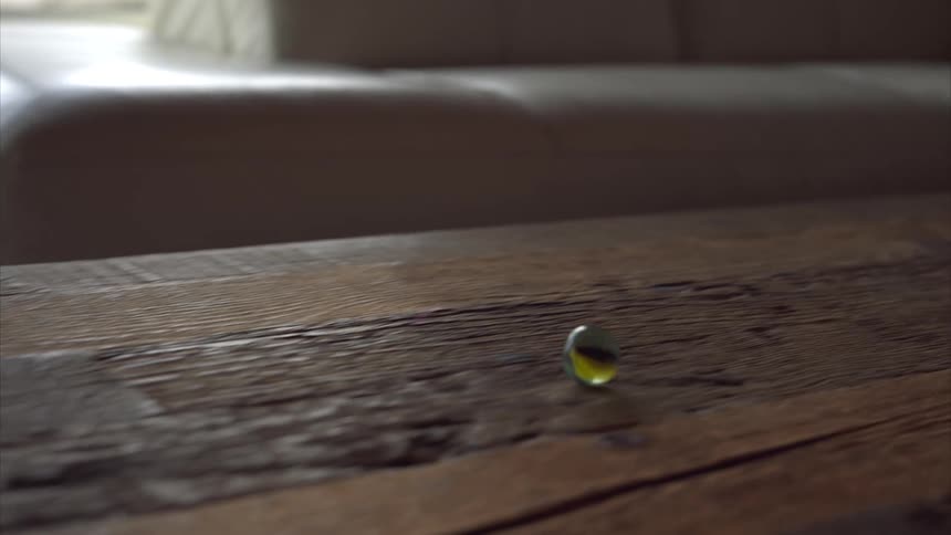 A girl rolling a marble on a wooden table