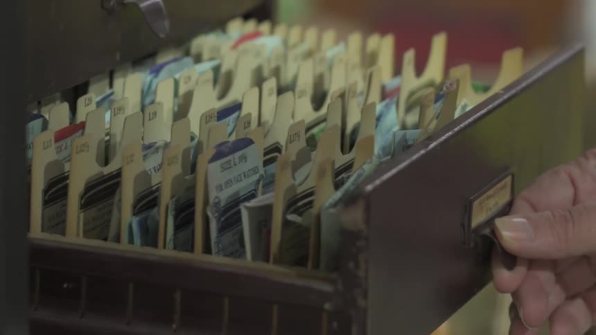 A hand opens the drawer of a filing cabinet