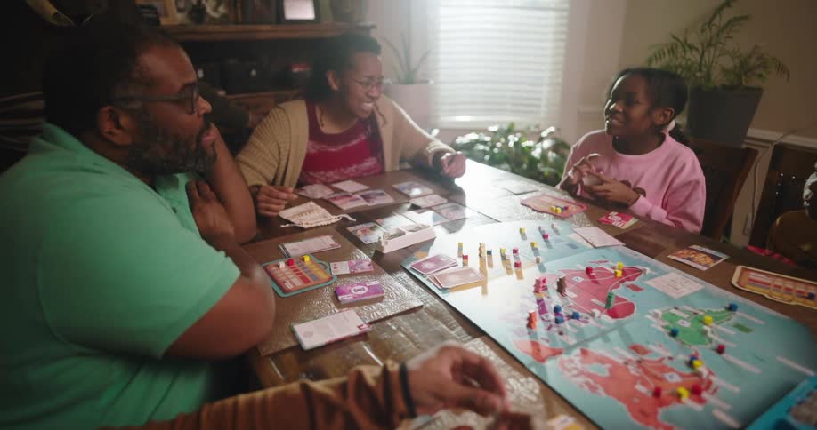 A family gathered around a table playing a boardgame at home