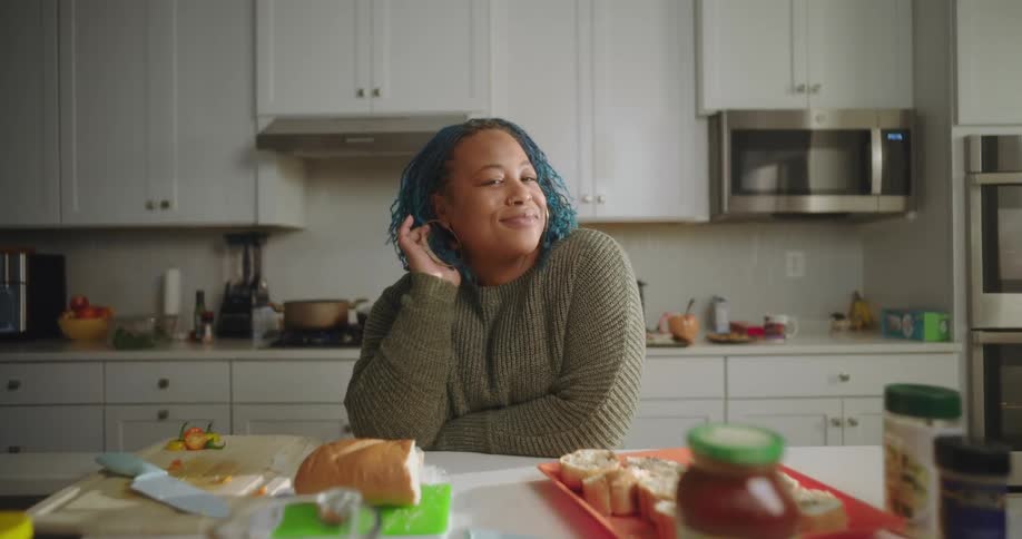 A woman leans on a counter full of food