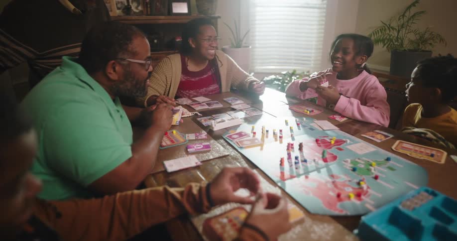 Happy family sitting at the table judging the board game war