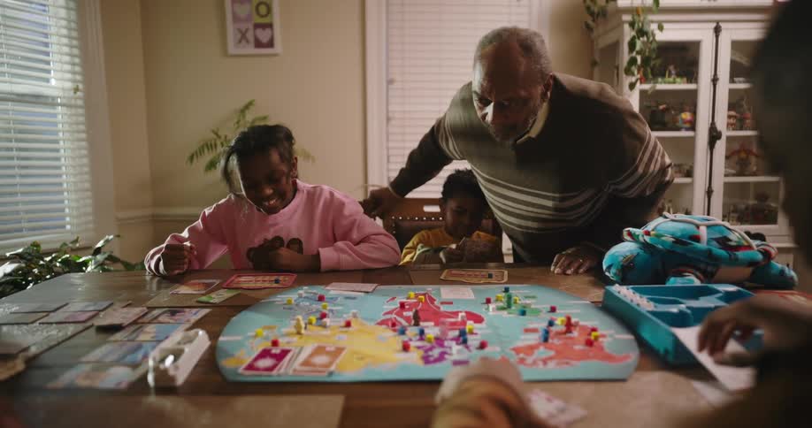 A family is sitting at a dining room table playing a board game