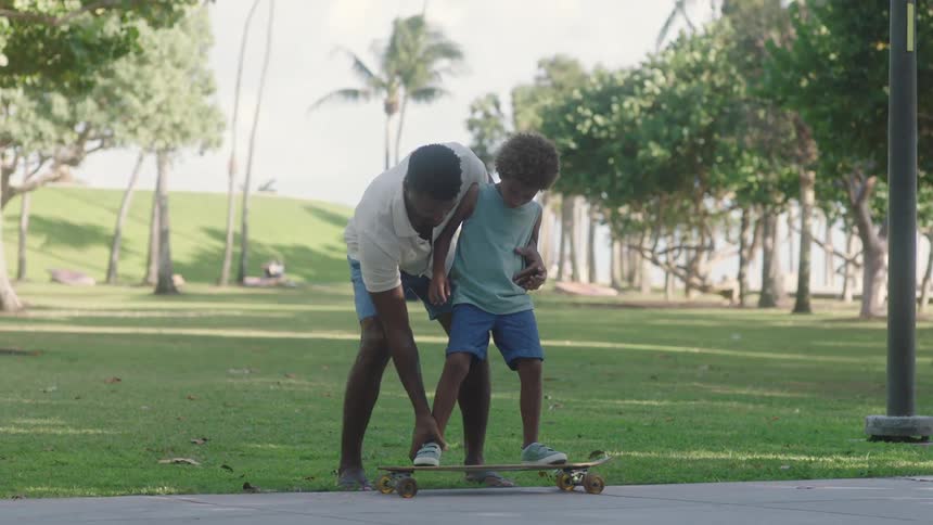 Father positioning his sons feet on the skateboard