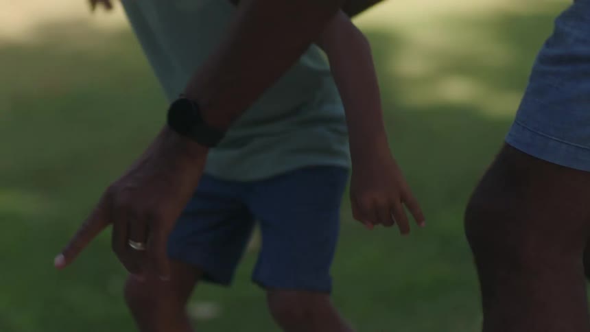 A father is pushing his son on a skateboard