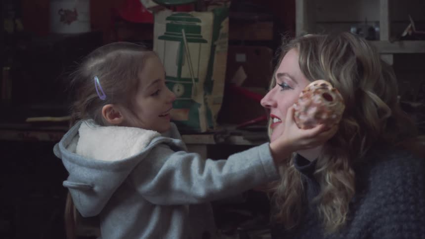 A daughter holds a sea shell up to her mothers ear