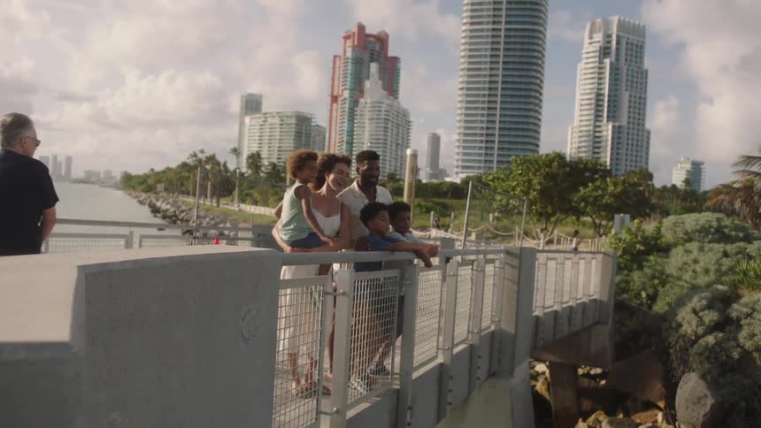 Family together on a seaside bridge with the skyscrapers of a metropolis in the background