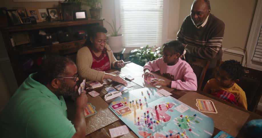A family gathered around a table playing a boardgame at home