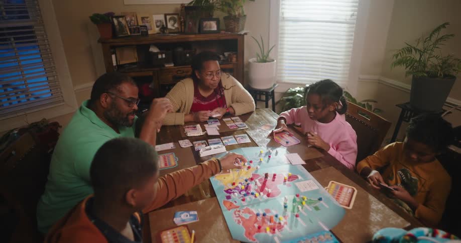 Family gathered around a wooden table playing board game
