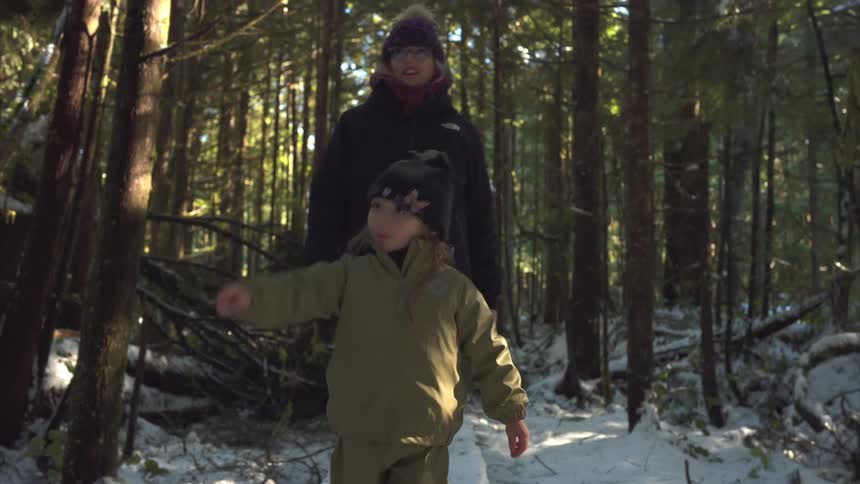 A girl points at things in the forest as she hikes