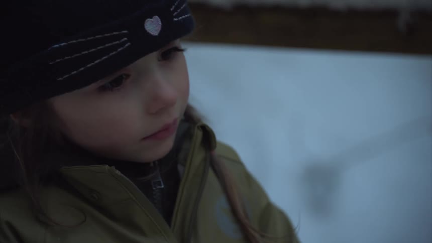 Girl wearing cold weather clothes looks up on a snowy winter day