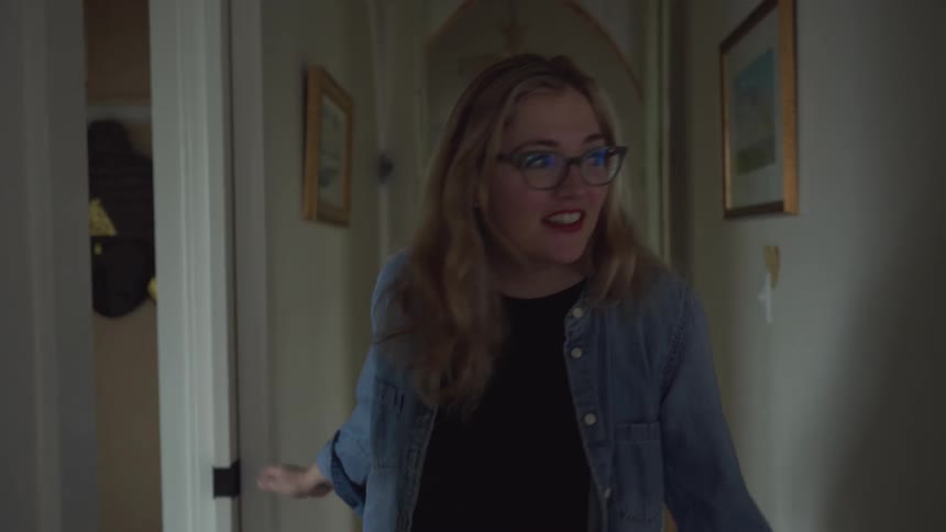 A woman walks through a corridor at home searching for someone near the doorways