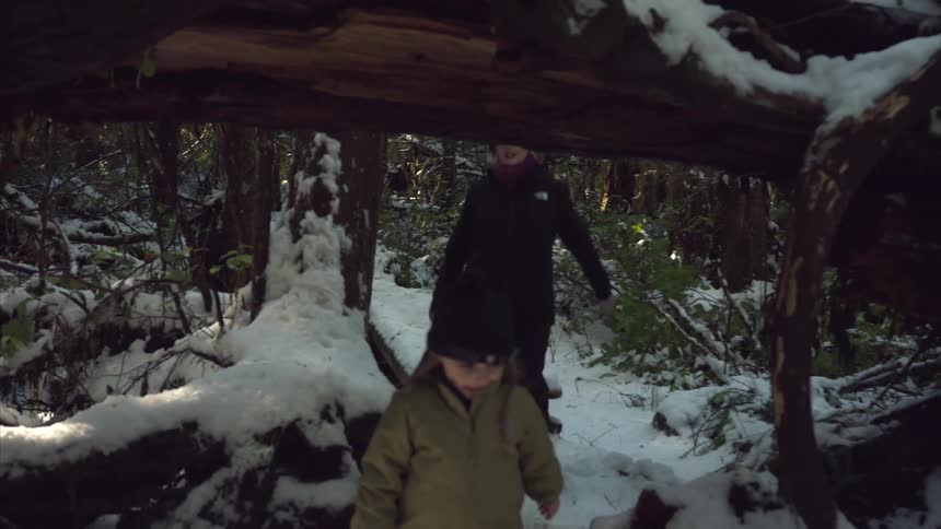 Mother and daughter walking along a snowy forest trail