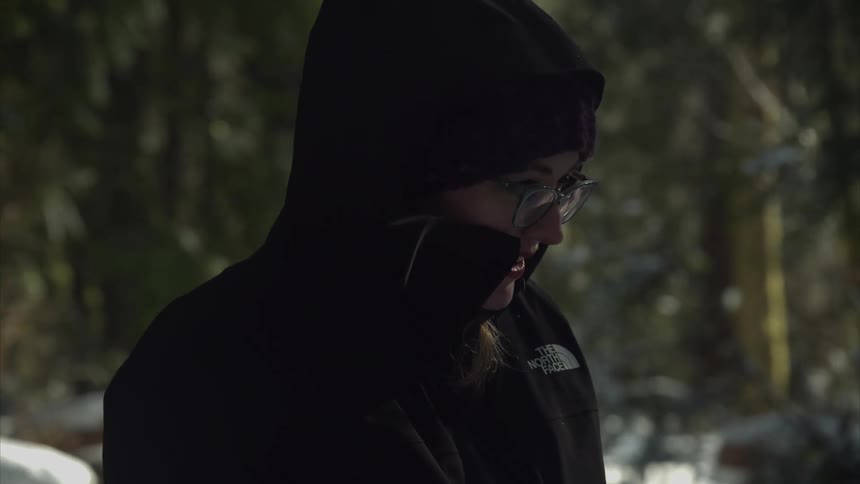 Woman wearing a coat stands outdoors on a snowy winter day