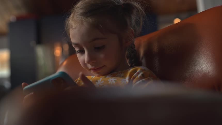 A girl sits in a chair on her phone