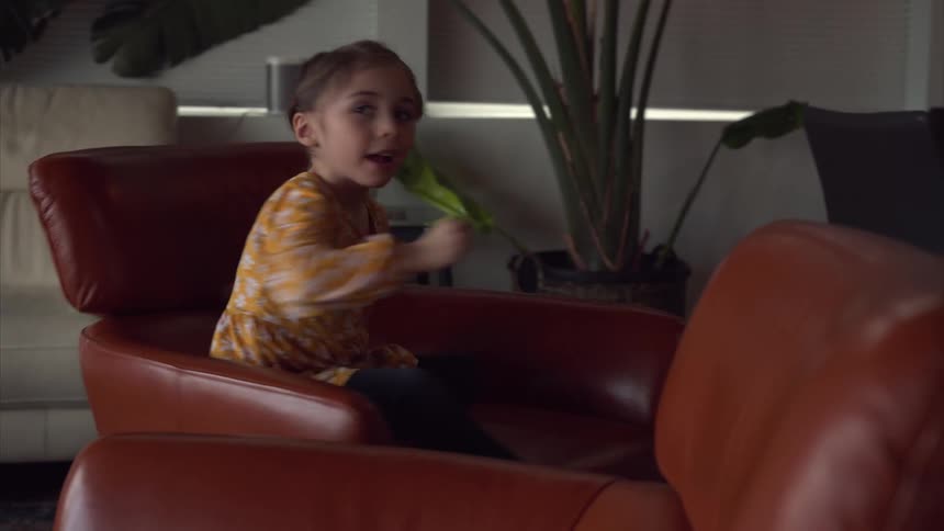 A little girl is spinning in a leather chair