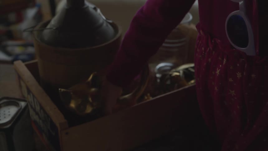 Happy little girl picking up objects from a box on a table