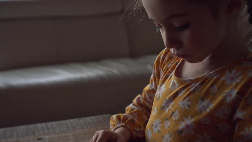 A girl playing with a marble on a wooden table