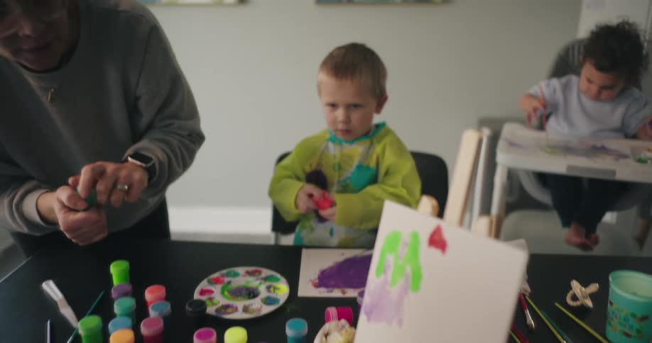 Woman caring for young children in a room with paint pots