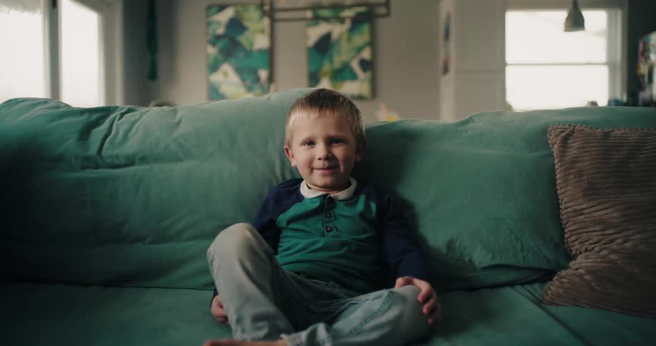 Boy with happy facial expression sitting on sofa in living room