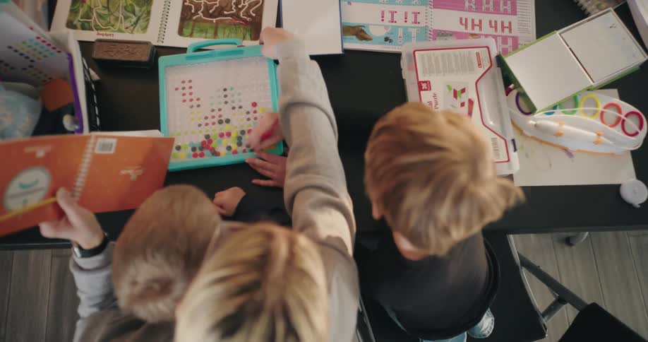A mother playing games with her children over a cluttered table at home