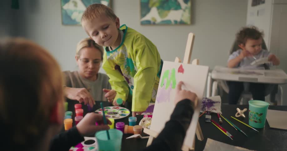 Children are painting as their mother watches