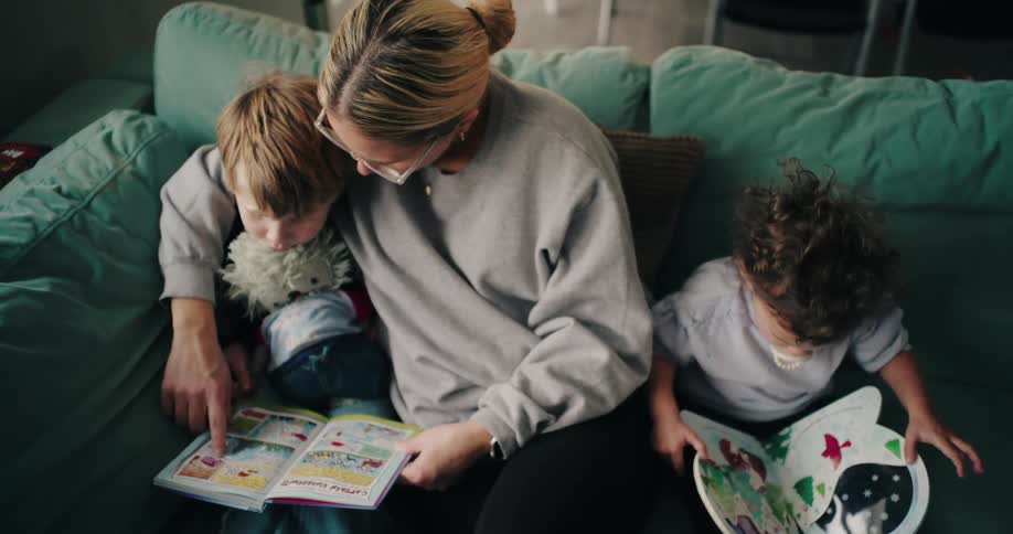 A mother is reading to her son on the couch
