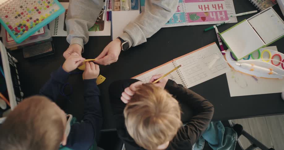Children playing with arts and crafts on a cluttered table or desk
