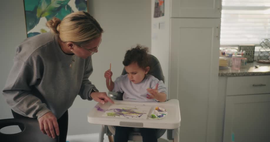 A mother is helping her daughter paint