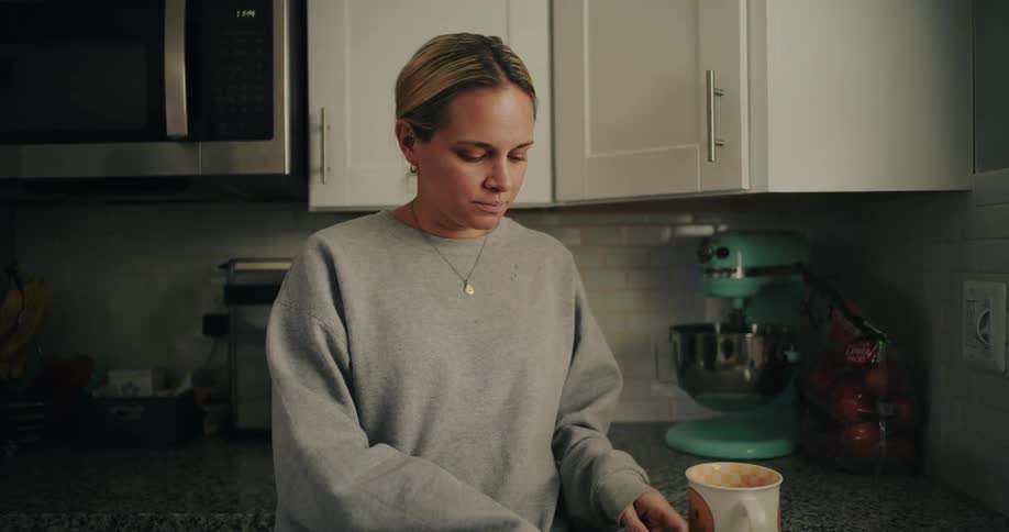 Woman covers her face with her hands visibly frustrated or worried in the kitchen