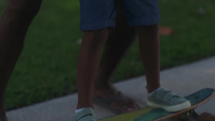 A father teaching his son to balance on a skateboard