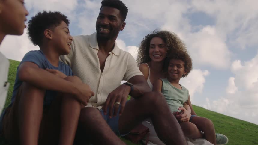 Happy family sitting on the grass talking