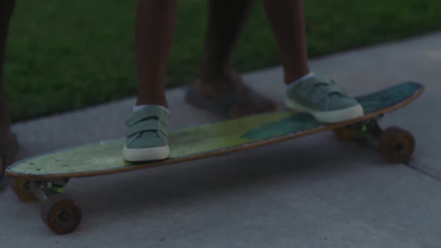A father is teaching his son how to skateboard