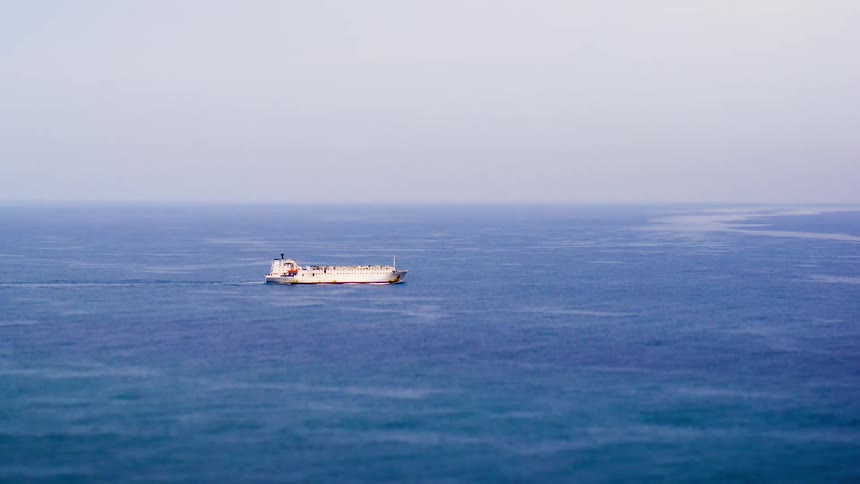 A white medium sized boat sails across the open sea