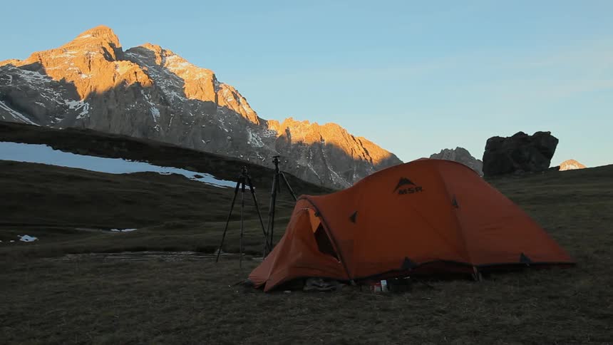 Camera tripods and tent set up in mountain wilderness