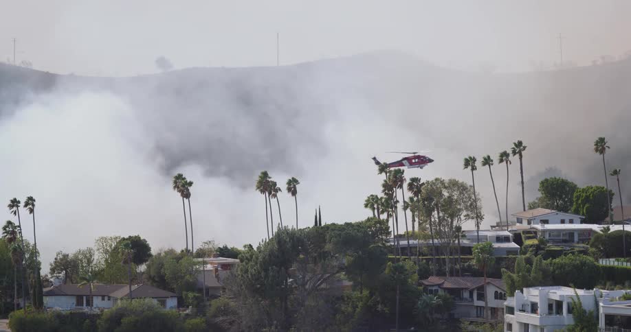 A rescue helicopter flies over the forest fire