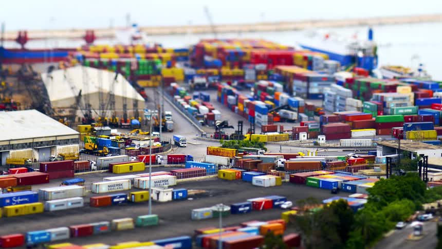 A tiltshift aerial view captures a bustling port with numerous colorful shipping containers trucks and ships