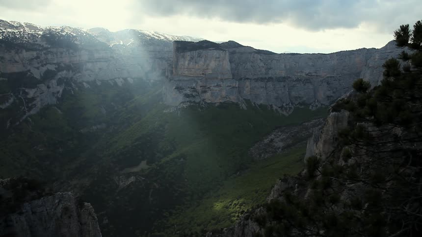 A mountain range has the sun peering down below