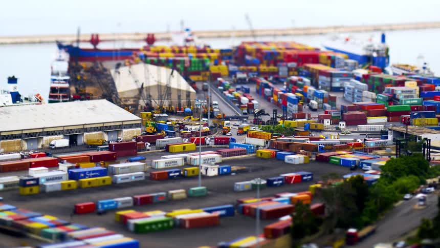 A tiltshift aerial view captures a bustling port with numerous colorful shipping containers trucks and ships