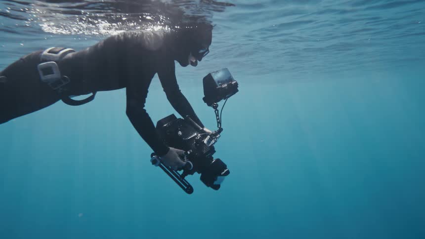 Diver carrying a professional video camera in the ocean