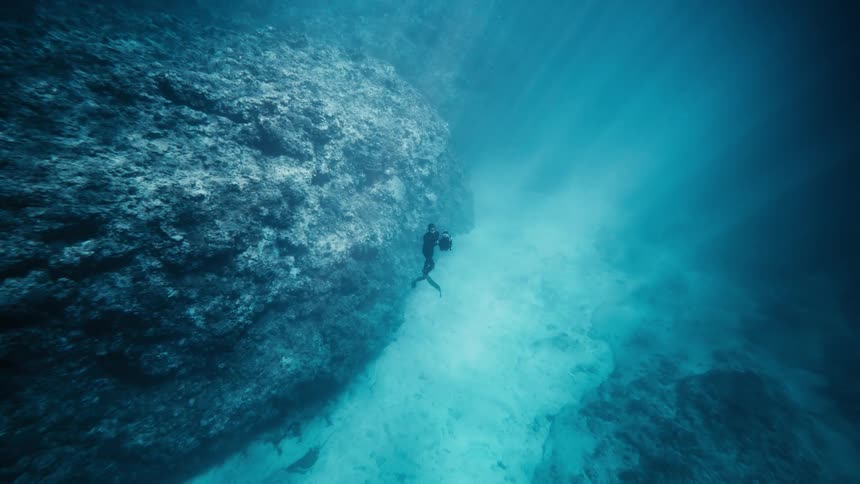 Diver in the depths of the ocean rising towards the surface
