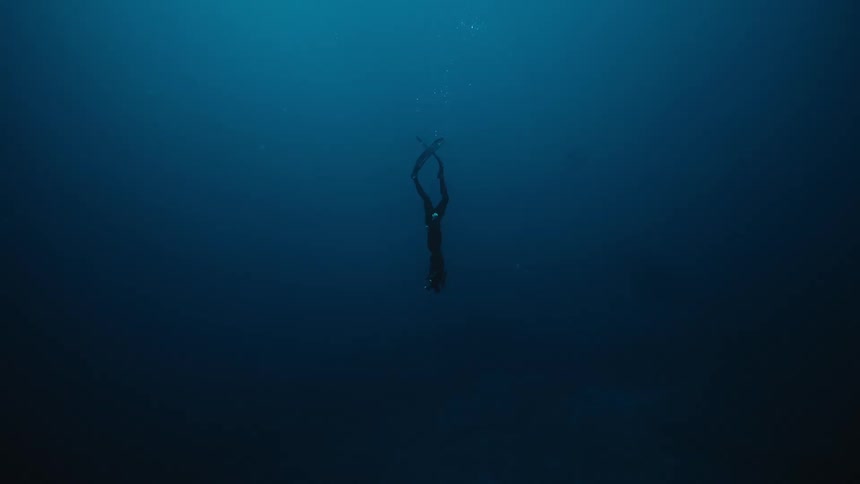 A diver is diving deep into the dark water