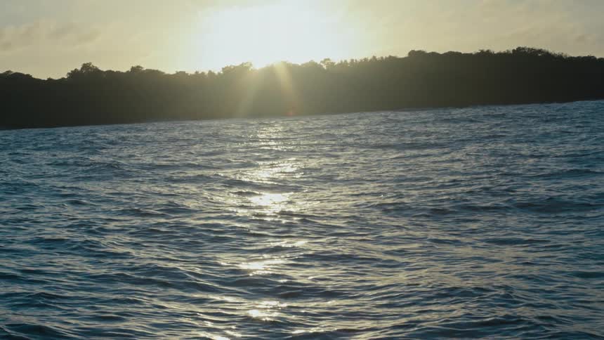 Ocean landscape with silhouette of mountains and sunrise on the horizon