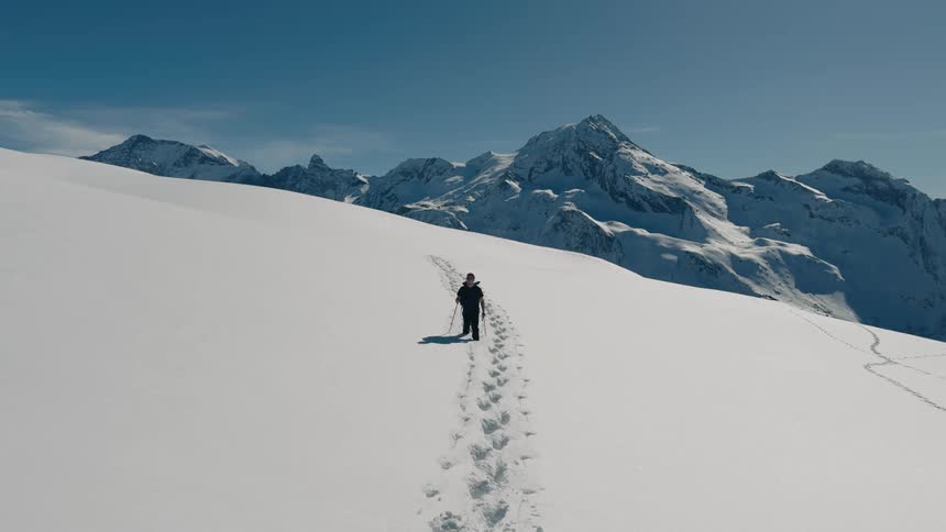 A person is hiking through snowy terrain on a mountain