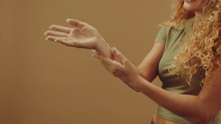 A person wearing a green crop top models a bracelet on their wrist against a solid beige background