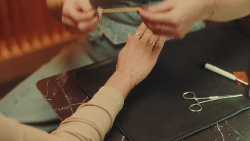 A jewelry is sizing a bracelet on a woman