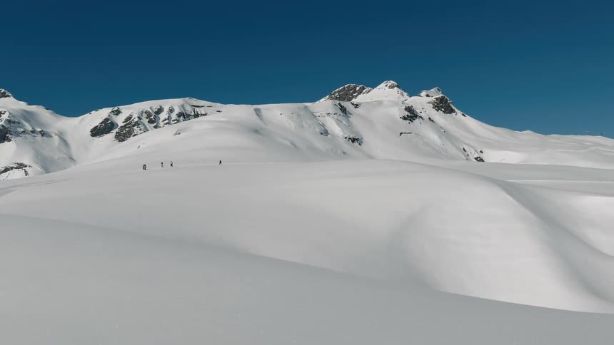A group of people is cross country skiing near a mountaintop