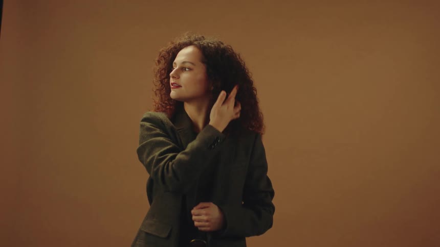 Woman with curly red hair running her hand through her hair