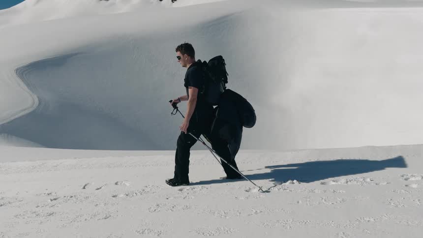 A man is hiking with a backpack through snowy terrain