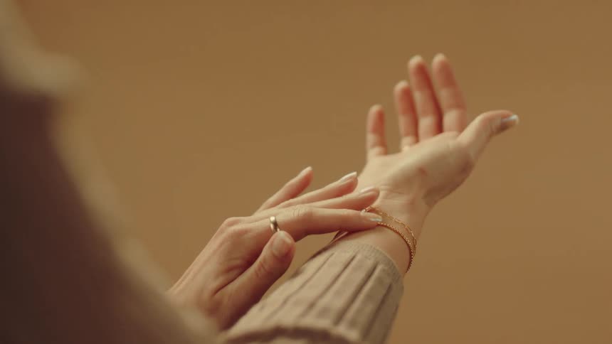 Woman is adjusting a gold bracelet on her right arm